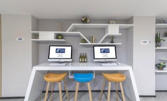 There is a computer desk with two monitors and one keyboard on top, along with other computers nearby at Holiday Inn Express Shanghai Gubei