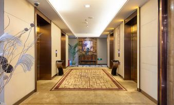 a hallway with a carpeted floor and multiple doors , leading to a room decorated with paintings at Z Hotel