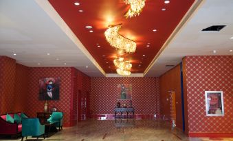 a red and gold room with a high ceiling and a chandelier hanging from the ceiling at Ximei Lucky Hotel