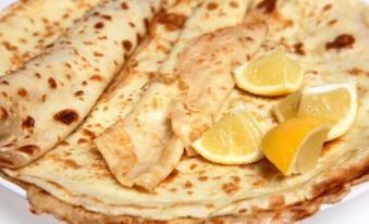 a close - up image of a stack of flat bread pancakes with lemon slices on top at The Dog Inn