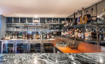 a well - stocked bar with various bottles and glasses , as well as a marble counter in the foreground at Twin Towers Inn