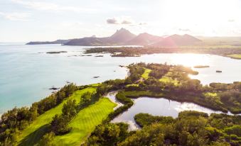 an aerial view of a golf course surrounded by water , with mountains in the background at Shangri-Las le Touessrok Resort and Spa