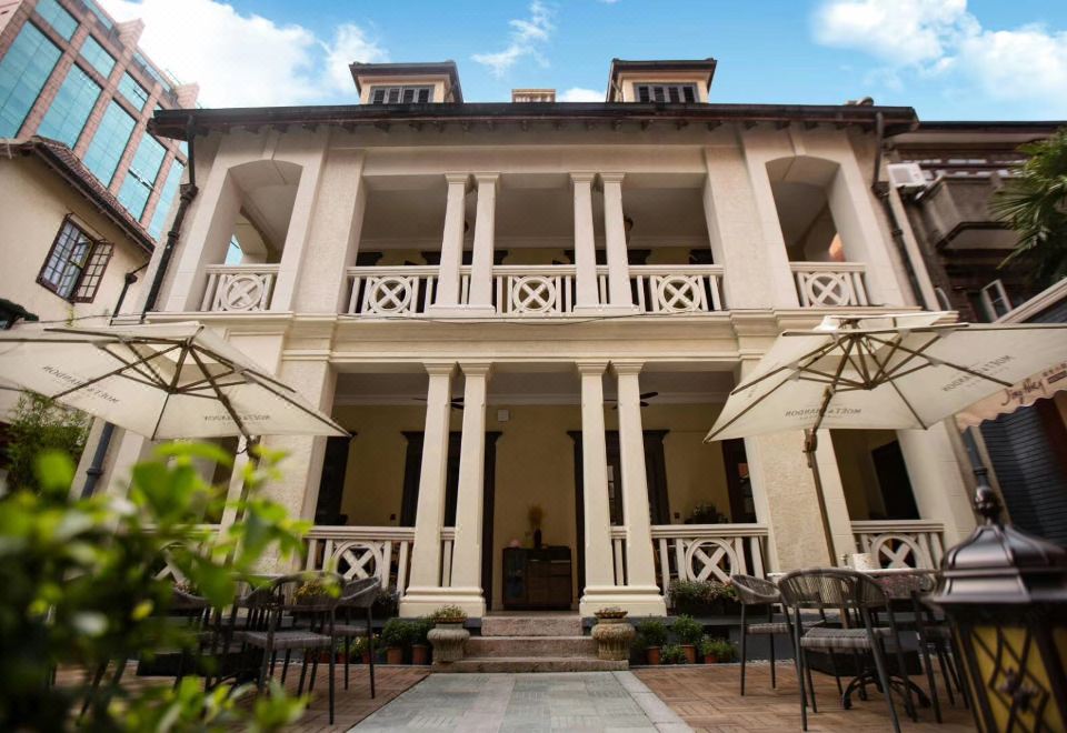 There is an outdoor dining area in front of a large building, furnished with chairs and tables at Huaihai Mansion