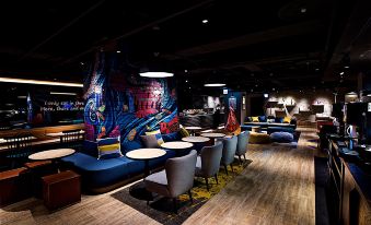 a modern restaurant with blue and yellow color scheme , seating arrangements , and an abstract mural on the wall at Just Sleep Ximending