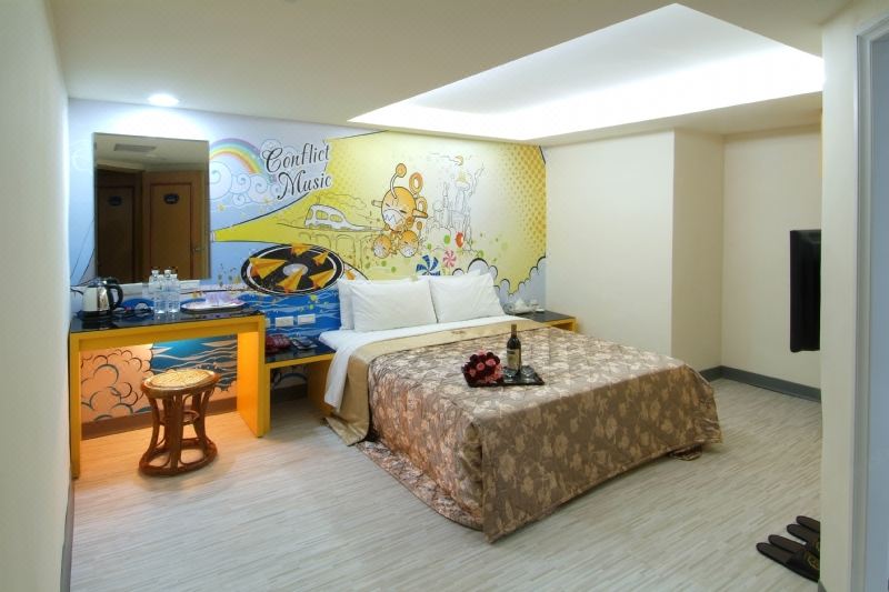 a large bed with a floral blanket is in the middle of a room with a colorful wall mural at Laurel Hotel