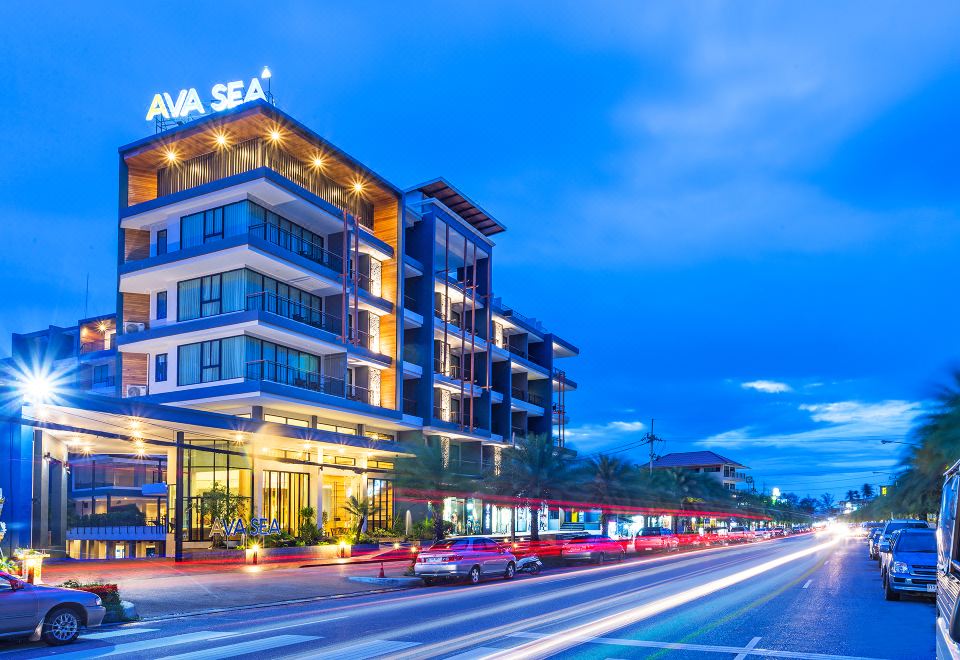 a city street at night , with a tall building in the background and numerous cars driving by at AVA SEA Resort Krabi