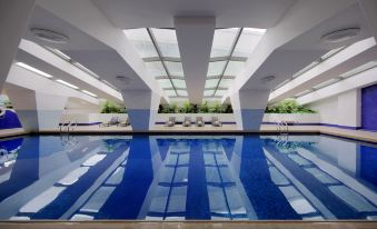 There is an indoor pool with blue water and a large ceiling window that overlooks other areas at Hotel Royal