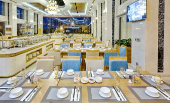 a modern restaurant interior with blue and white decor , wooden tables , chairs , and a television at Paris Deli Danang Beach Hotel