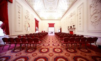 a large , ornate room with a red carpet and rows of red chairs arranged for a meeting or event at Lumley Castle Hotel