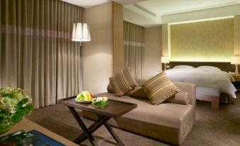 A room with a large bed and a table in the middle, with an open space beside it at City Suites (Taoyuan Gateway)