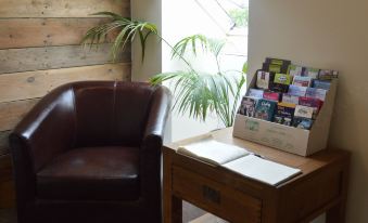 a brown leather chair is next to a wooden table with a box of books on it at The Anchor Inn