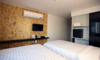The bedroom has two beds and a wall-mounted TV at KSTAR METRO Hotel