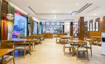 a large , well - lit restaurant with wooden tables and chairs arranged in an open space - like manner at Gengting Hotel