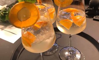a dining table with three wine glasses filled with white wine , accompanied by slices of orange and mint at Arte Hotel Salzburg