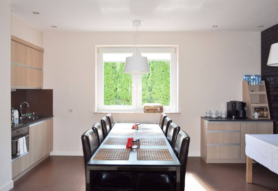 a dining room with a long table and chairs , a window , and a kitchen area at Best East