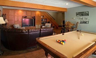 a cozy living room with a pool table , couches , chairs , and a tv mounted on the wall at Walnut Waters Bed & Breakfast