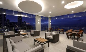 a modern living room with couches , chairs , and tables arranged around a large window overlooking the city at Hompton Hotel by The Beach