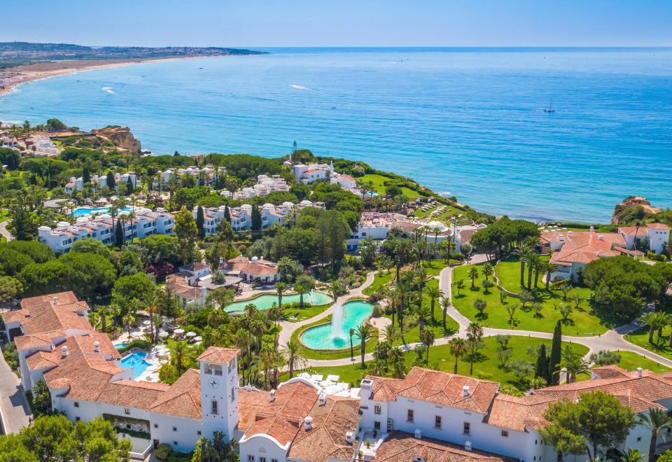 a bird 's eye view of a resort with a pool surrounded by buildings and the ocean at Vila Vita Parc