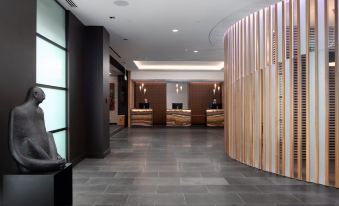 a modern hotel lobby with wooden reception desks and a large screen at the end at Rydges Wellington Airport, an EVT hotel