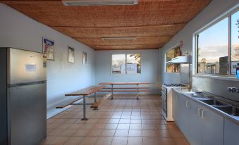 a large , empty room with wooden beams and tiled floors has several benches and a counter at Borderland Wodonga Holiday Park
