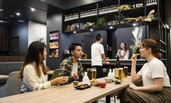 A group is seated at a table in an outdoor restaurant, with other individuals standing and eating at Grids Tokyo Ueno Hotel&Hostel