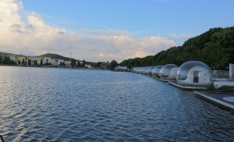 a long row of clear domed boats floating on a body of water , surrounded by trees and buildings at Lucen