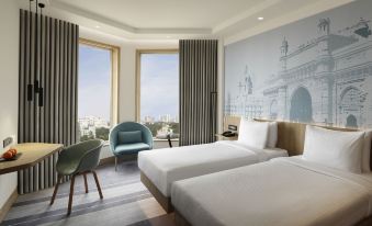 a hotel room with two beds , a window offering a view of the city , and a blue chair at Novotel Mumbai Juhu Beach