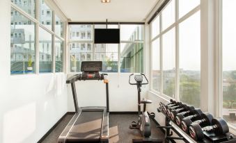 a small gym with a treadmill , stationary bike , and weights is shown in the image at Ibis Styles Bekasi Jatibening
