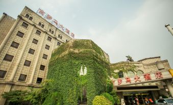 a building with a large tree growing on its side , surrounded by greenery and a stone wall at Rome Hotel