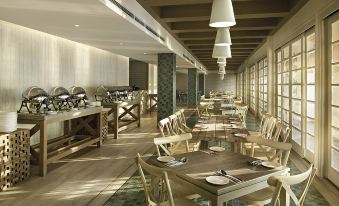 a dining room with wooden tables and chairs , along with a kitchen area in the background at Resorts World Langkawi
