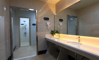 There is a bathroom with two sinks and a large mirror in the middle, located on tiled walls at Guangzhou Baiyun Airport Passenger Time Lounge (T1 Terminal Store)