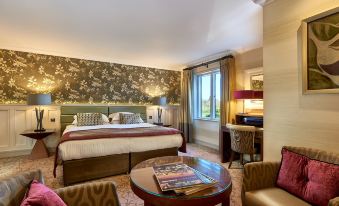 a hotel room with a king - sized bed , a couch , and a tv . also a dining table in the room at Grosvenor Pulford Hotel & Spa