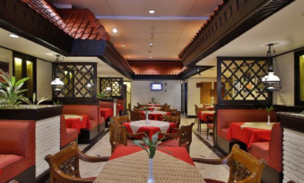 a dining room with a table surrounded by chairs , and a television mounted on the wall at Jayakarta Hotel Jakarta