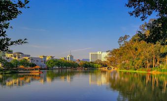 a serene lake with a wooden bridge and trees in the foreground , reflecting the city skyline at Lakeside Hotel