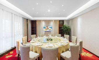 a large round dining table surrounded by chairs in a room with a red carpet at Kusatsu Hotel