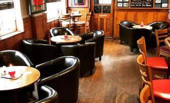 a room with wooden walls and floors has black chairs and tables , along with a chalkboard menu at The Baskerville