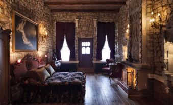 a cozy bedroom with a stone wall , a large bed , and a fireplace , as well as a desk and chairs at Sacred House