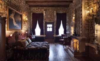 a room with a stone wall , wooden floor , and furniture including a couch , coffee table , and chairs at Sacred House