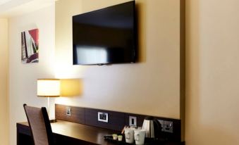 a hotel room with a large flat - screen tv mounted on the wall above a desk at Premier Inn Glasgow (Bearsden)