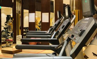 a well - equipped gym with multiple treadmills and exercise bikes lined up against a wall , providing a comfortable environment for people to exercise at Sheraton Qinhuangdao Beidaihe Hotel