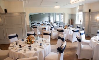 a large dining room with white tablecloths and chairs , ready for a wedding reception or other special event at The Old Lodge