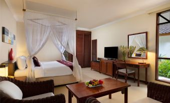 a modern hotel room with a canopy bed , couch , dining table , and other furniture , including a bed , tv , desk , and mirror at Holiday Resort Lombok