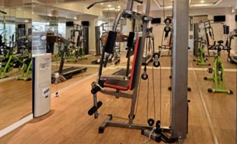 a well - equipped gym with various exercise equipment , such as treadmills , weight machines , and stationary bikes at Savero Hotel Depok