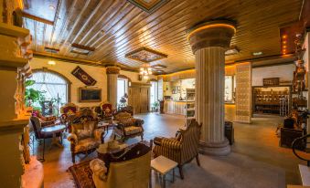 a large , well - lit living room with a high ceiling and wooden columns , featuring various pieces of furniture and a staircase at Kapadokya Hill Hotel & Spa (12+)