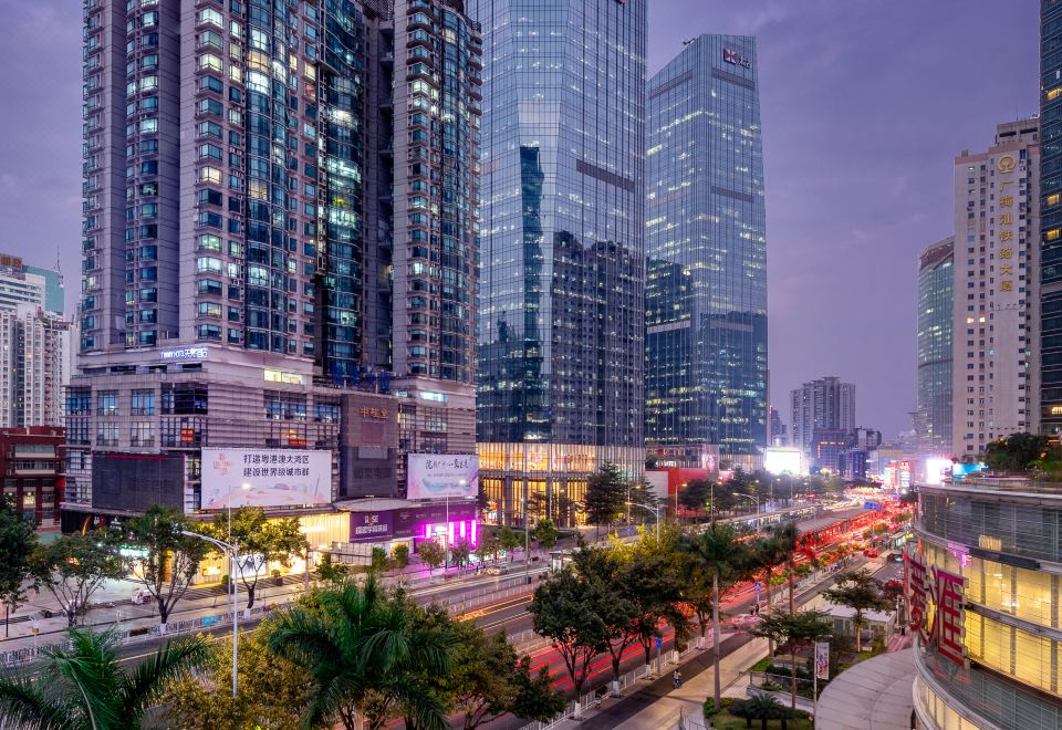 A city street with tall buildings and busy traffic during dusk or twilight at Timmy Apartment Hotel