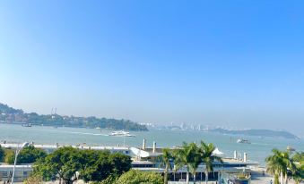 The balcony offers a scenic view of the water, beach, and city, with towering buildings in the foreground at Chunguang Hotel