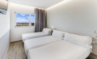 a hotel room with two beds , one on the left and one on the right side of the room at B&B Hotel Barcelona Viladecans