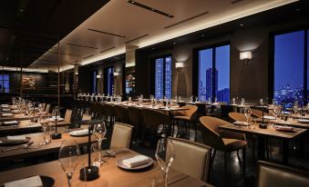 a large , modern restaurant with many tables and chairs set up for diners , offering a stunning view of the city skyline at The Royal Park Hotel Iconic Osaka Midosuji