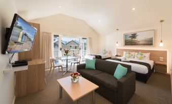 a modern hotel room with a couch , bed , and table , as well as a balcony offering views of the sea at Boathouse Resort Studios and Suites