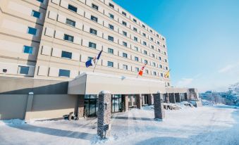 a large building with multiple flags flying on top , surrounded by snow and a clear blue sky at The Explorer Hotel